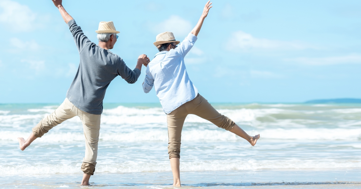 senior couple jumping on the beach happy in love