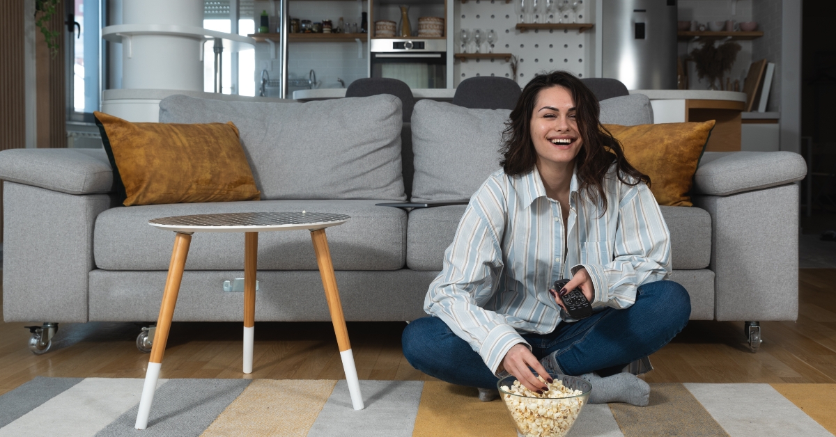 woman enjoys her free day watching tv and eating popcorn