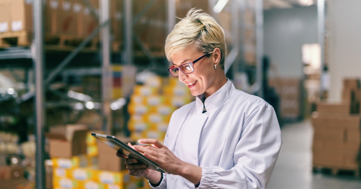woman in white uniform using tablet in warehouse