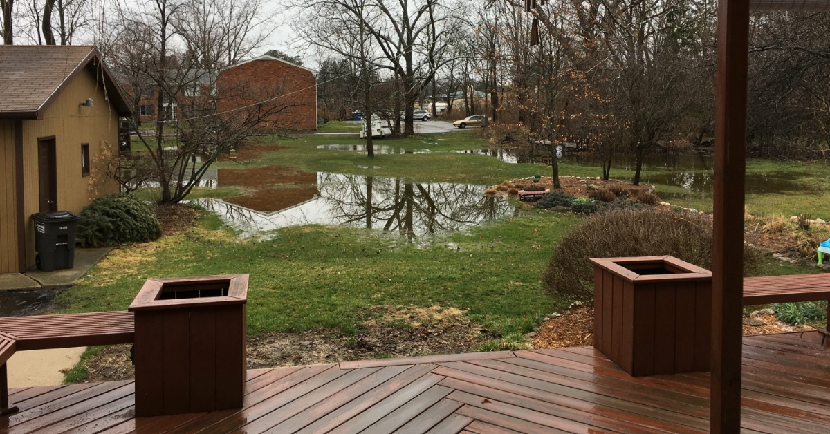 green yard with flooding besides cottages