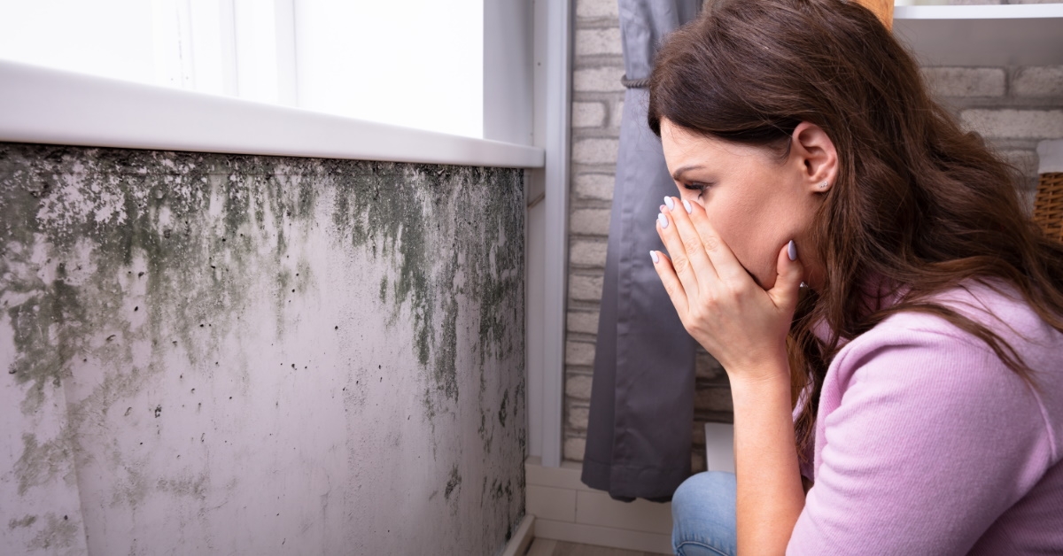 sad woman looking at mold on wall