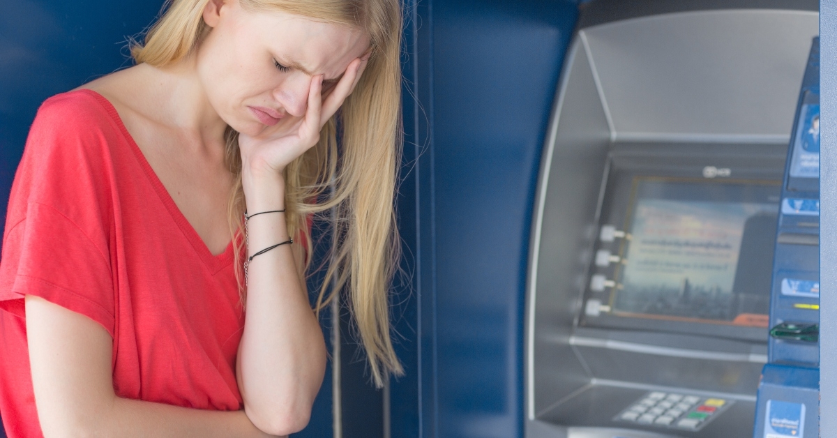 sad woman standing in front of a ATM bank machine
