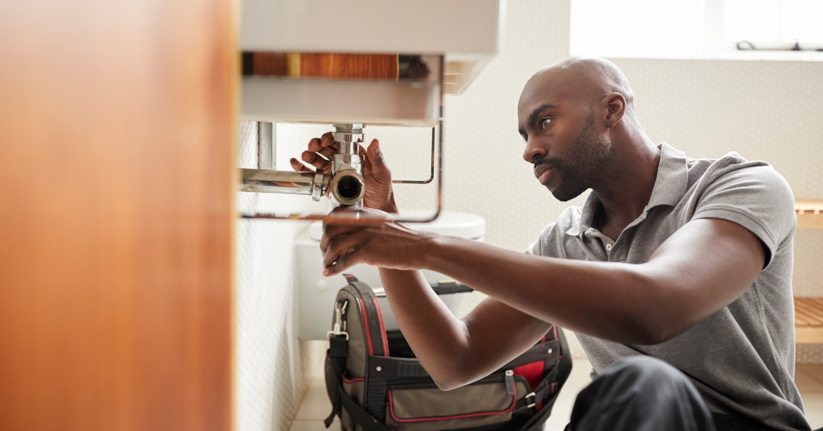 plumber sitting on the floor fixing a bathroom sink