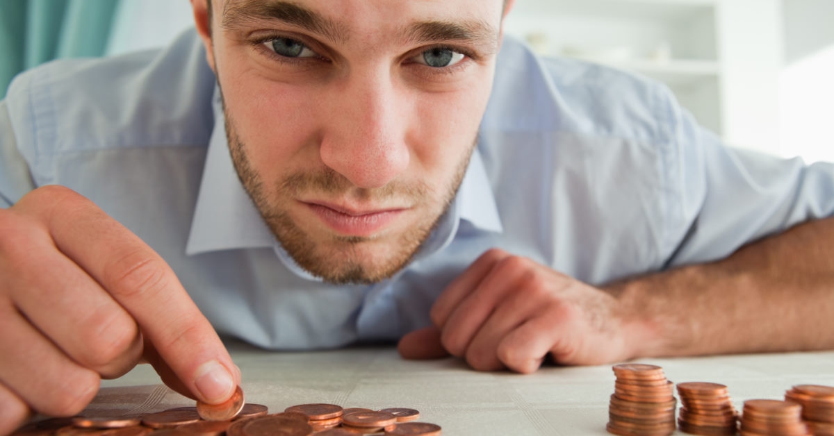 desperate businessman counting pennies on table