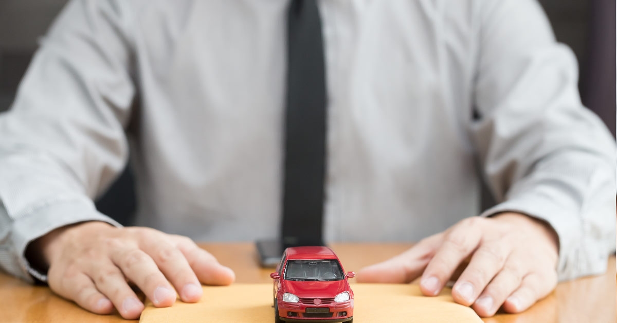 man sitting with documents with red car on top