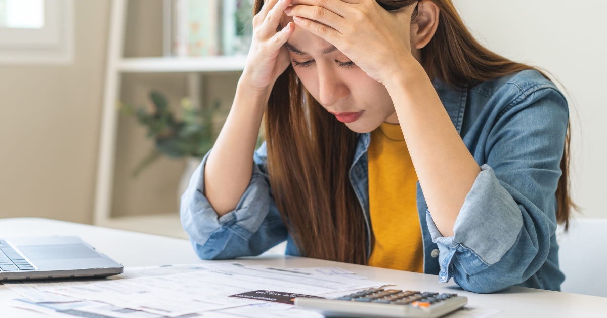 woman holds her head stressed while looking at papers