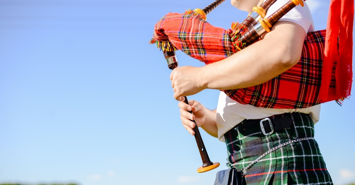 male playing Scottish traditional pipes outdoors