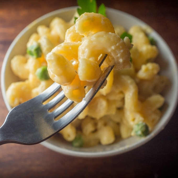 Bowl of mac and cheese and fork in front with mac and cheese 