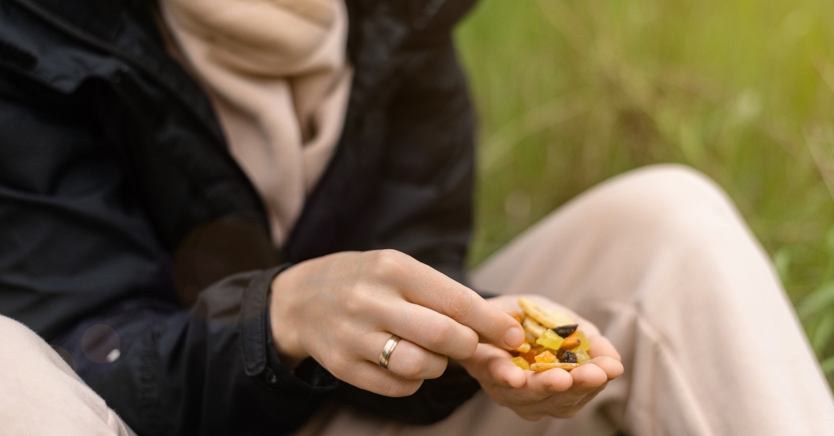 woman holds various dried fruits and nuts in her hand