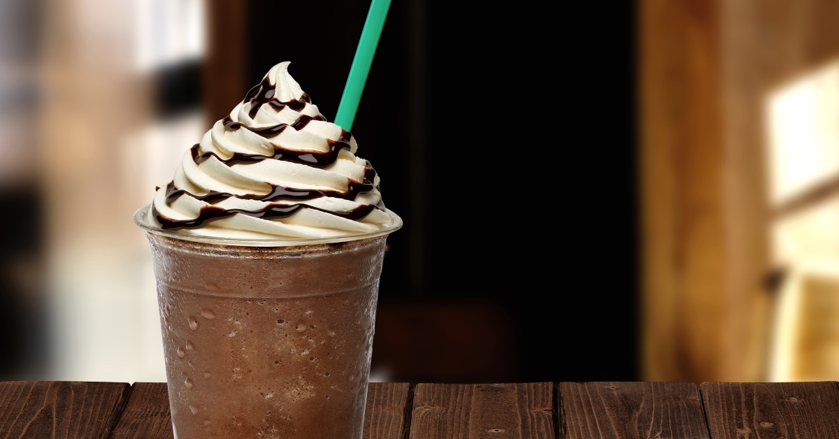 Frappuccino in takeaway cup on wooden table
