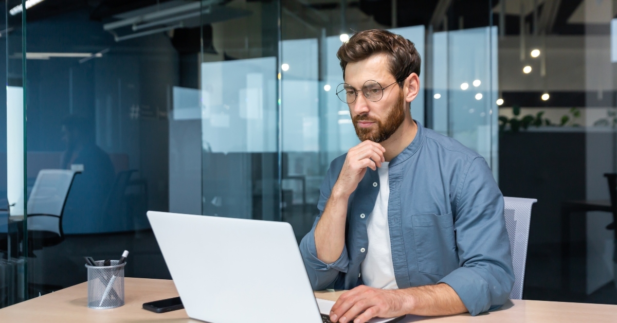 man with beard is using laptop at work