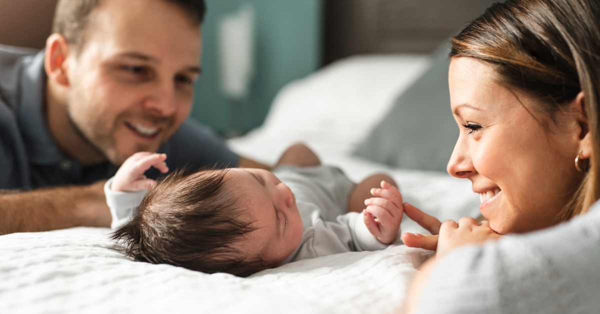 couple with newborn baby on bed