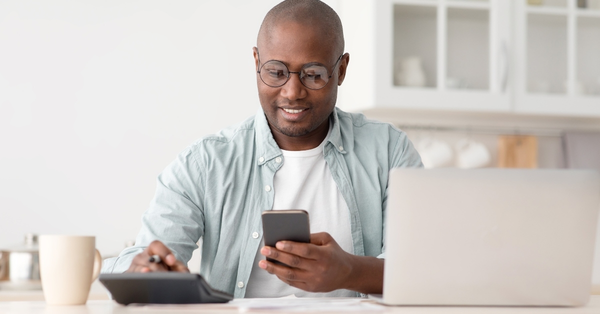 man using calculator phone and laptop 