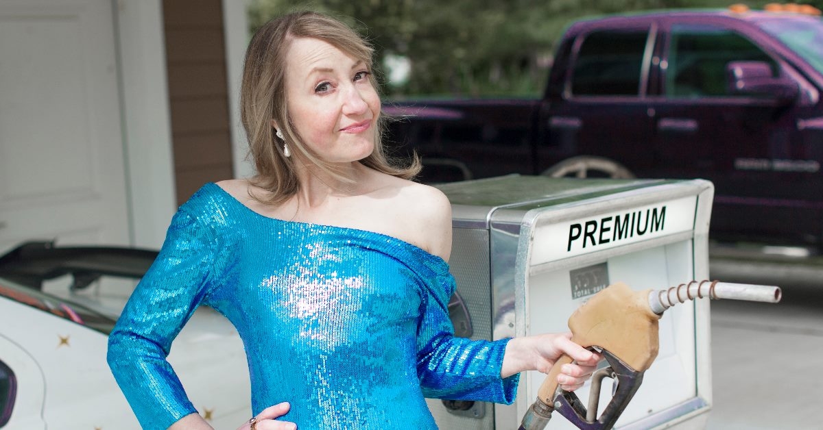 woman in blue dress filling gas in car at gas station