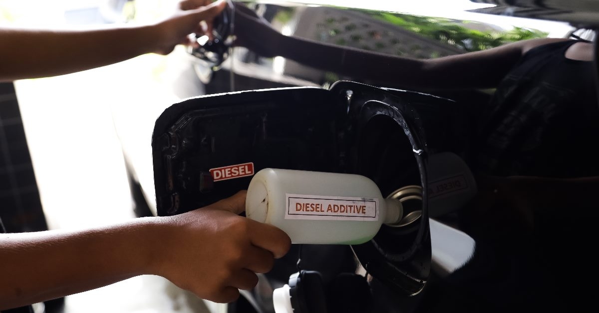 hand adding diesel to a cars gas tank