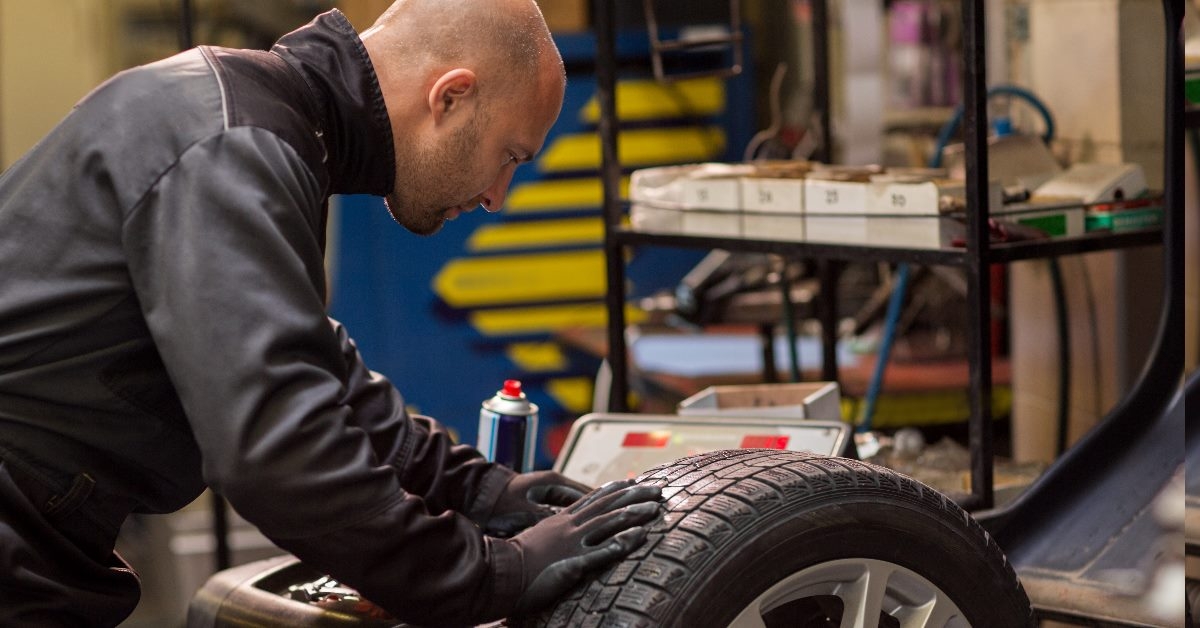 mechanic in workshop checking air pressure of tyre