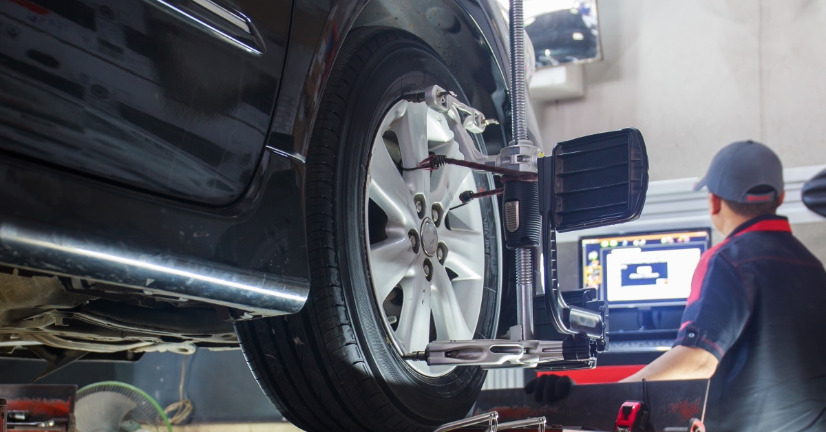 mechanic in workshop checking wheel alignment on computer 