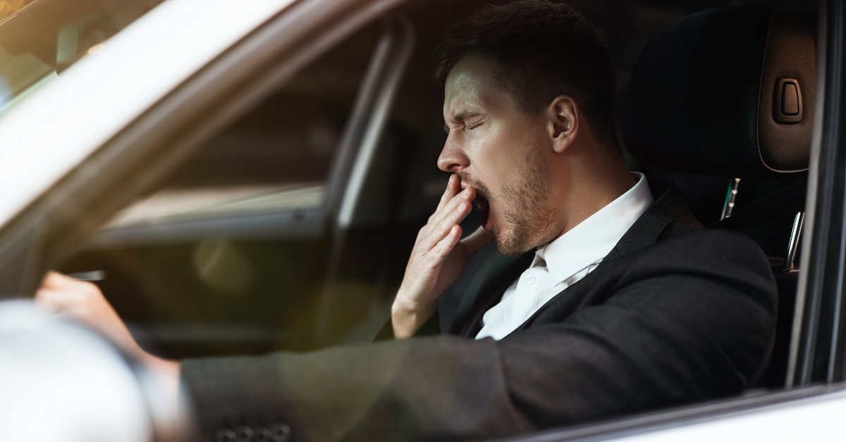 businessman looks tired yawning while siting in his car
