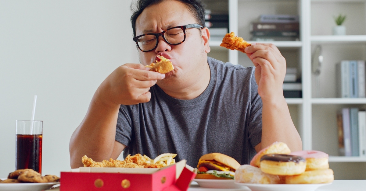 fat man enjoys to eat unhealthy junk food
