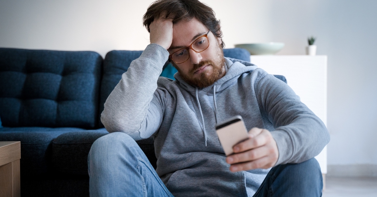 worried guy holding cellphone at home
