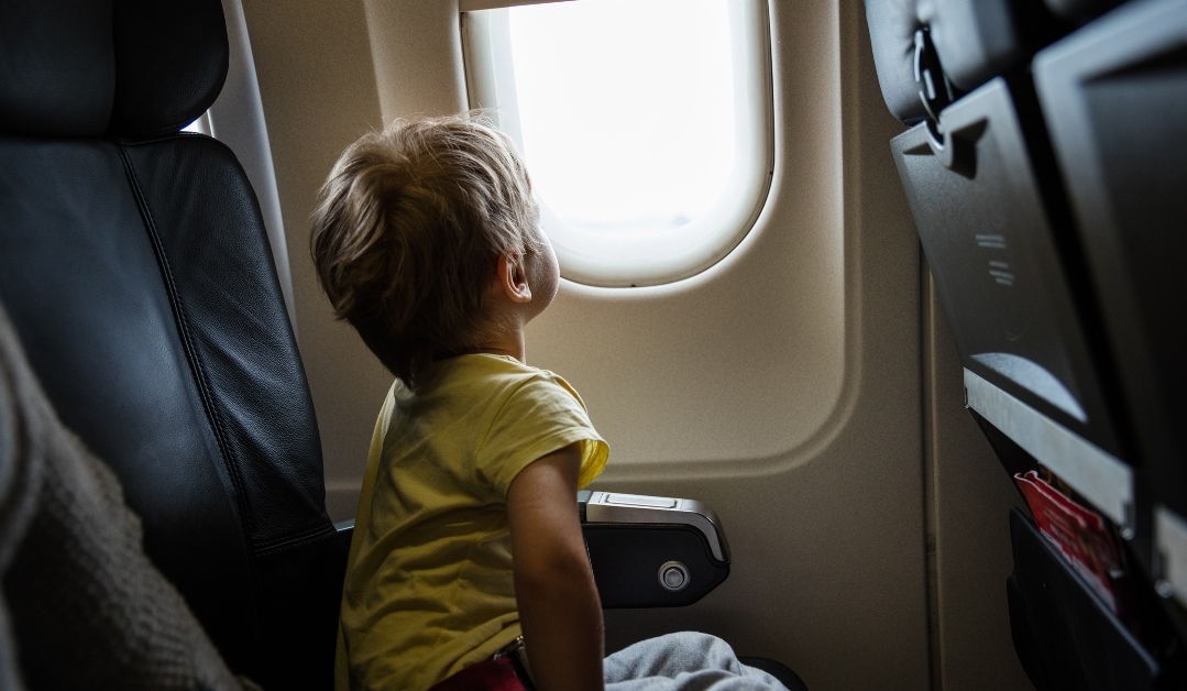 boy looking out of window in airplane