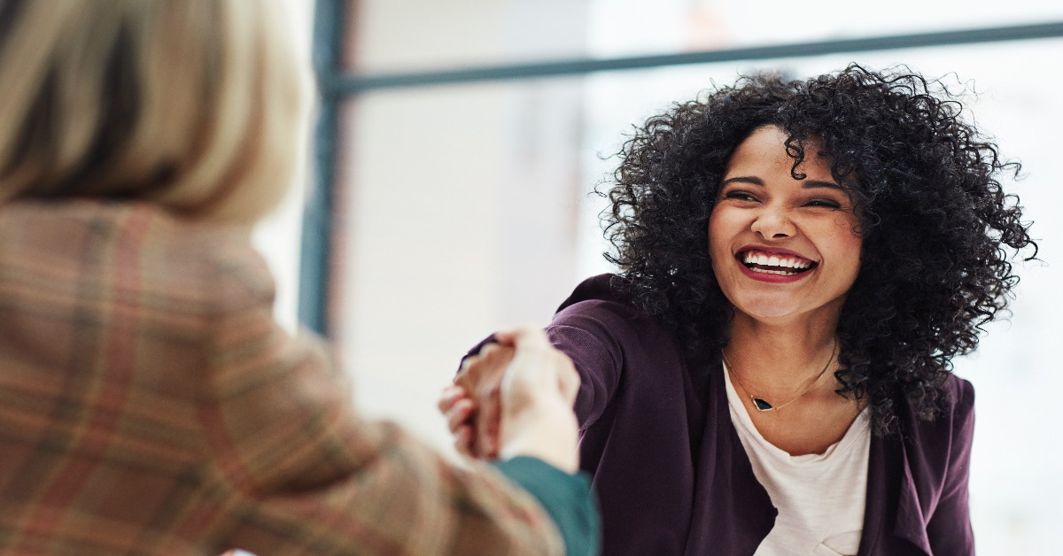 women at workplace laughing and shaking hands with each other