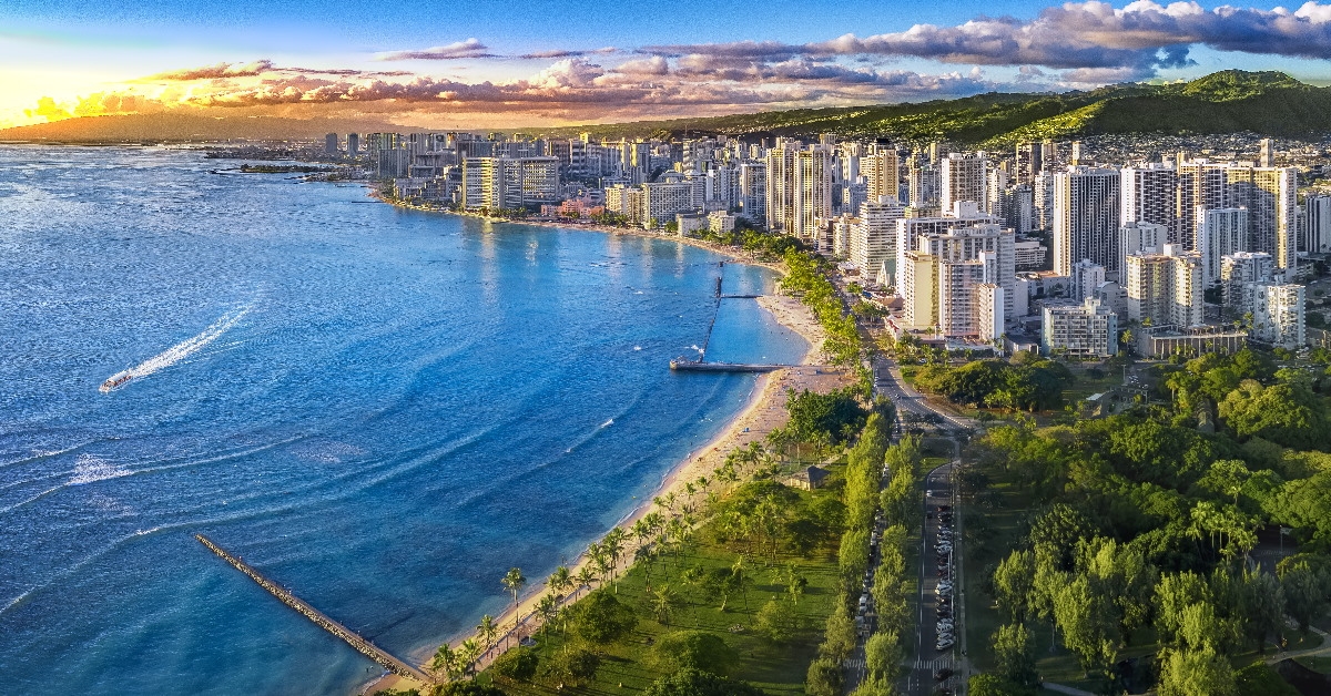 honolulu skylines in front of white sandy beach with green trees