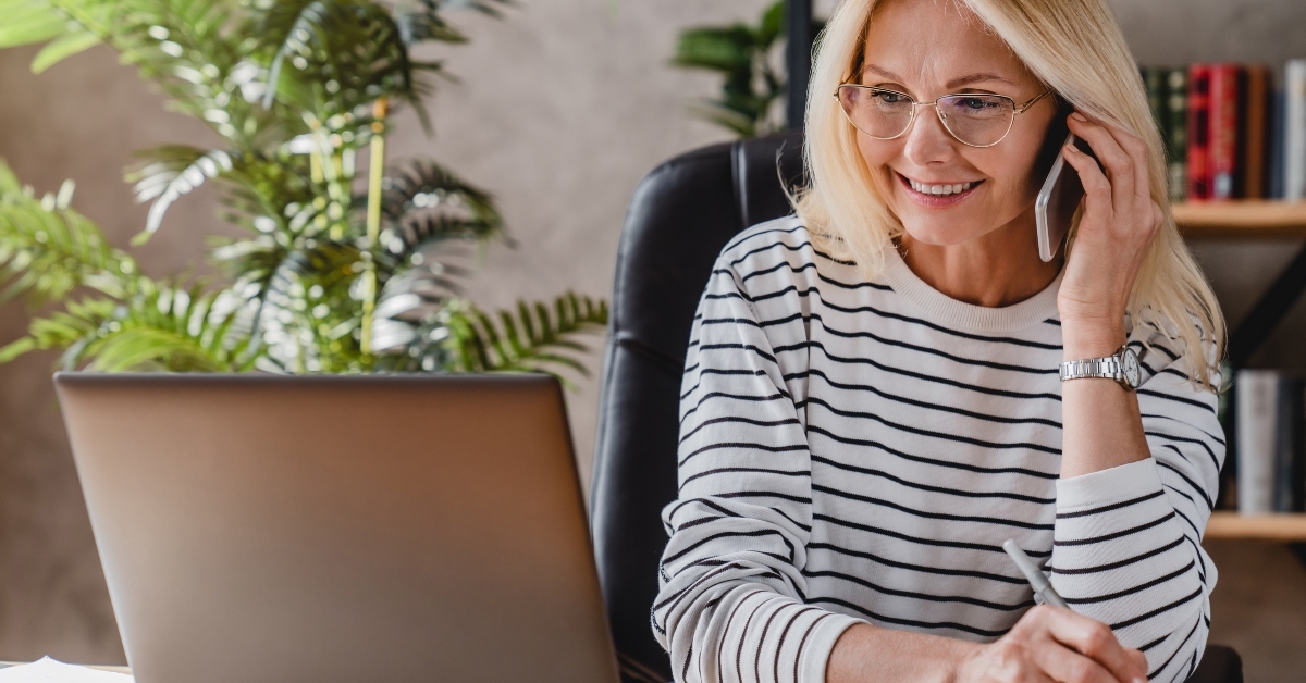 elderly businesswoman speaking on smartphone while working
