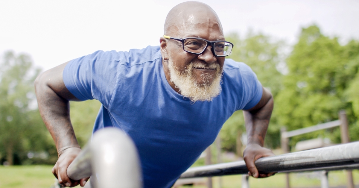 senior male doing push ups on bars outdoors