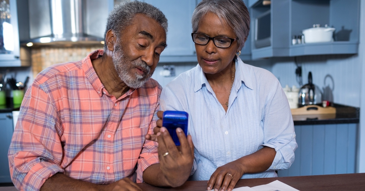 senior couple using calculator in kitchen