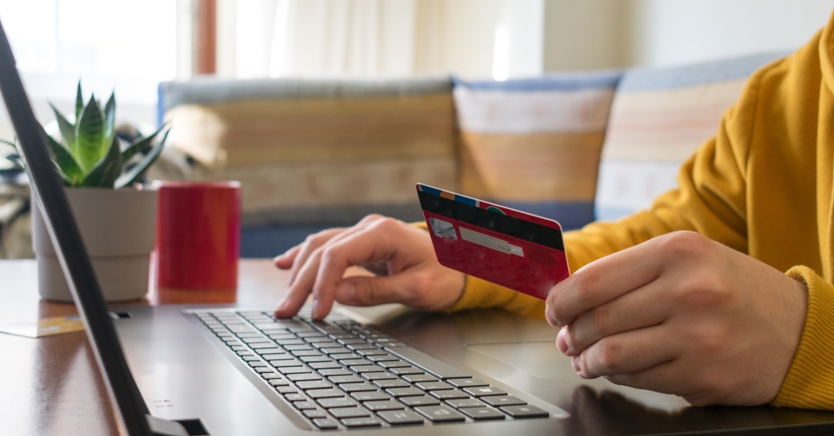 man online shopping on laptop with a red credit card