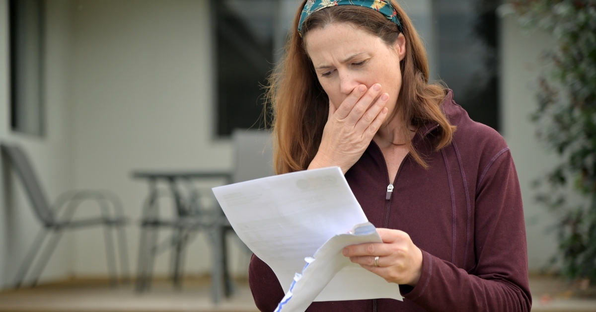 upset woman reading a letter in home front yard