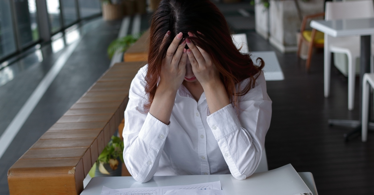 stressed businesswoman covering face with hands