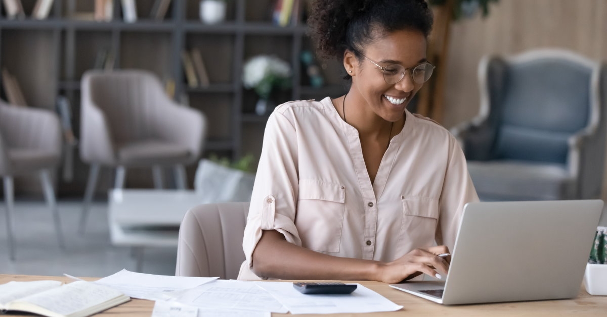happy african american girl sitting on table using laptop 