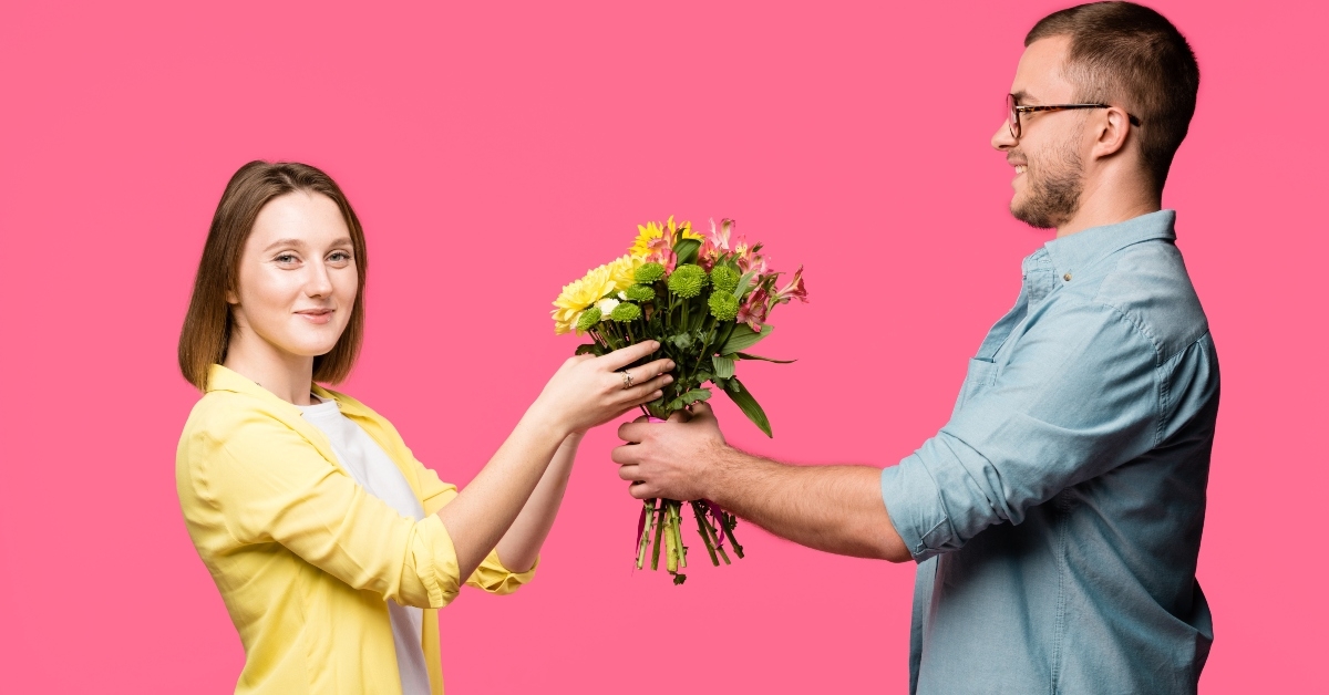 man presenting bouquet of flowers to smiling woman