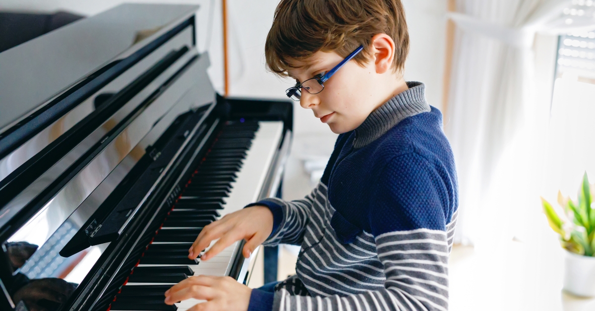 school boy with glasses playing piano in living room