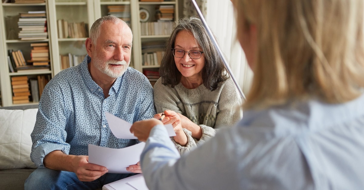 agent showing papers to senior couple sitting across table