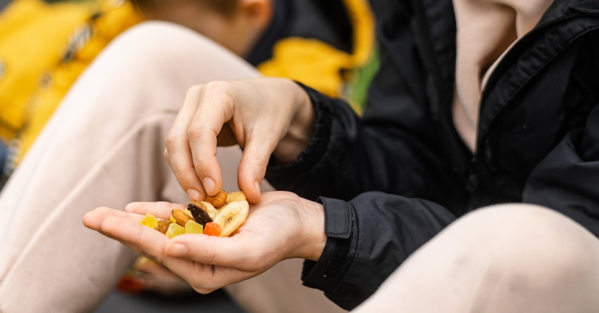 woman holds various dried fruits and nuts in her hand