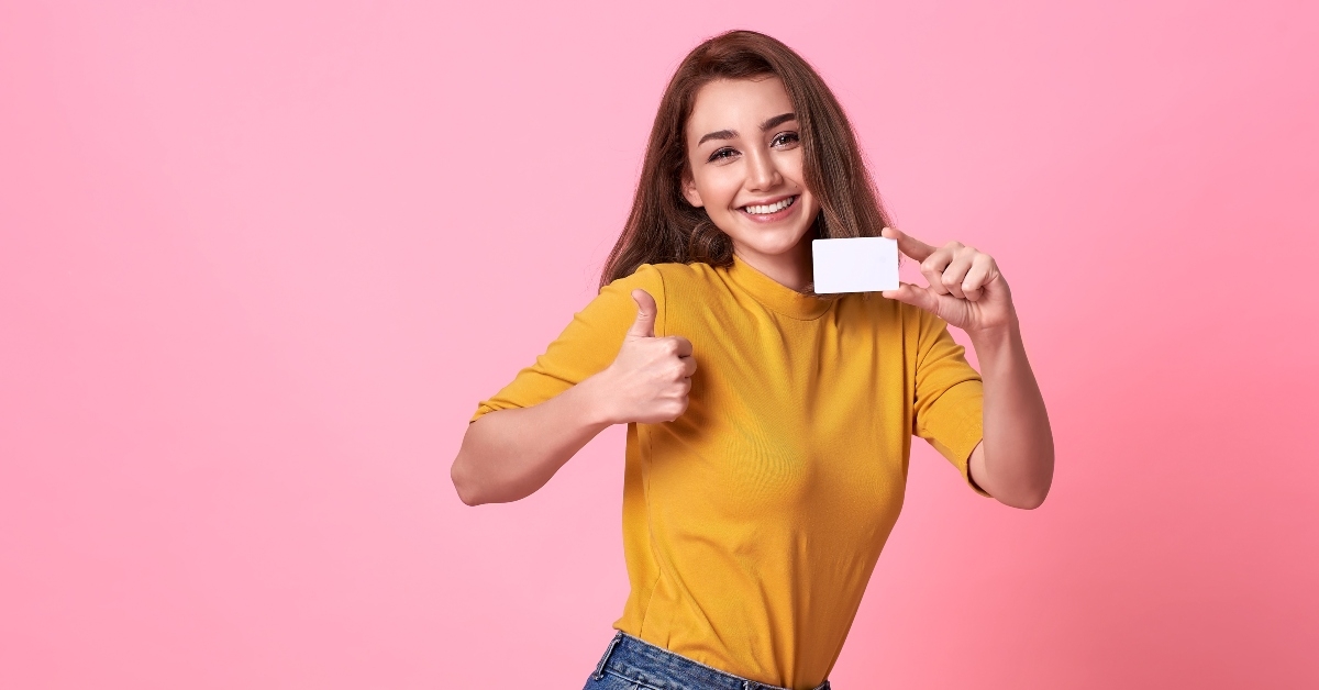 woman in yellow shirt showing credit card
