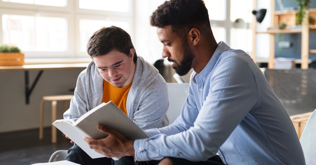 man with Down syndrome and his tutor studying indoor