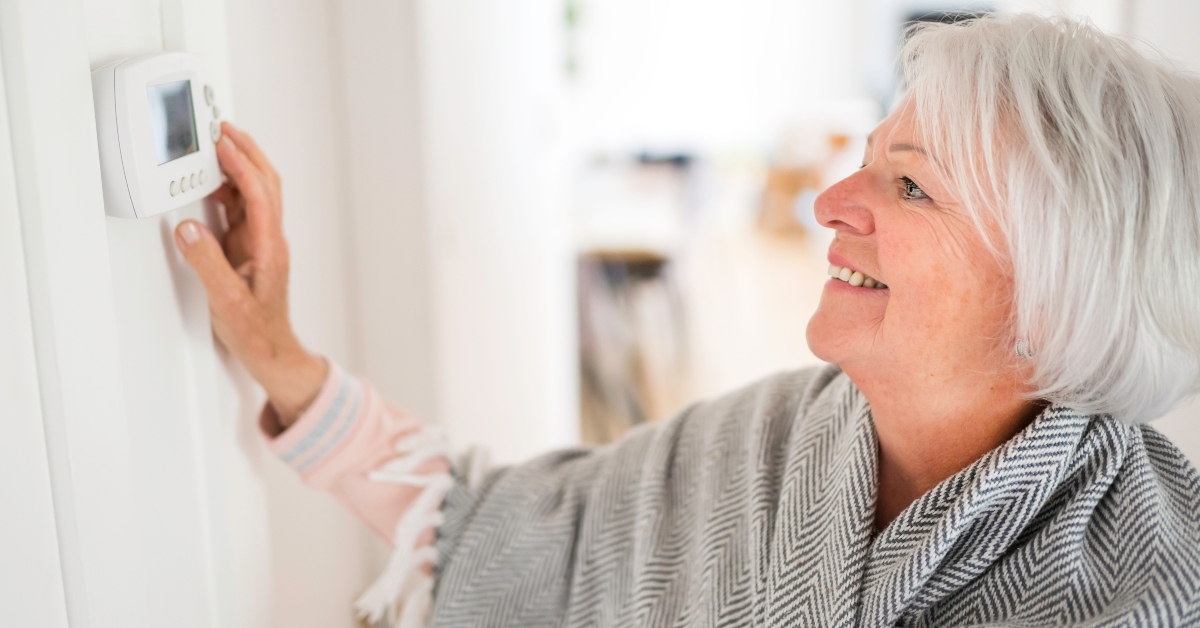 senior woman adjusting her thermostat at home