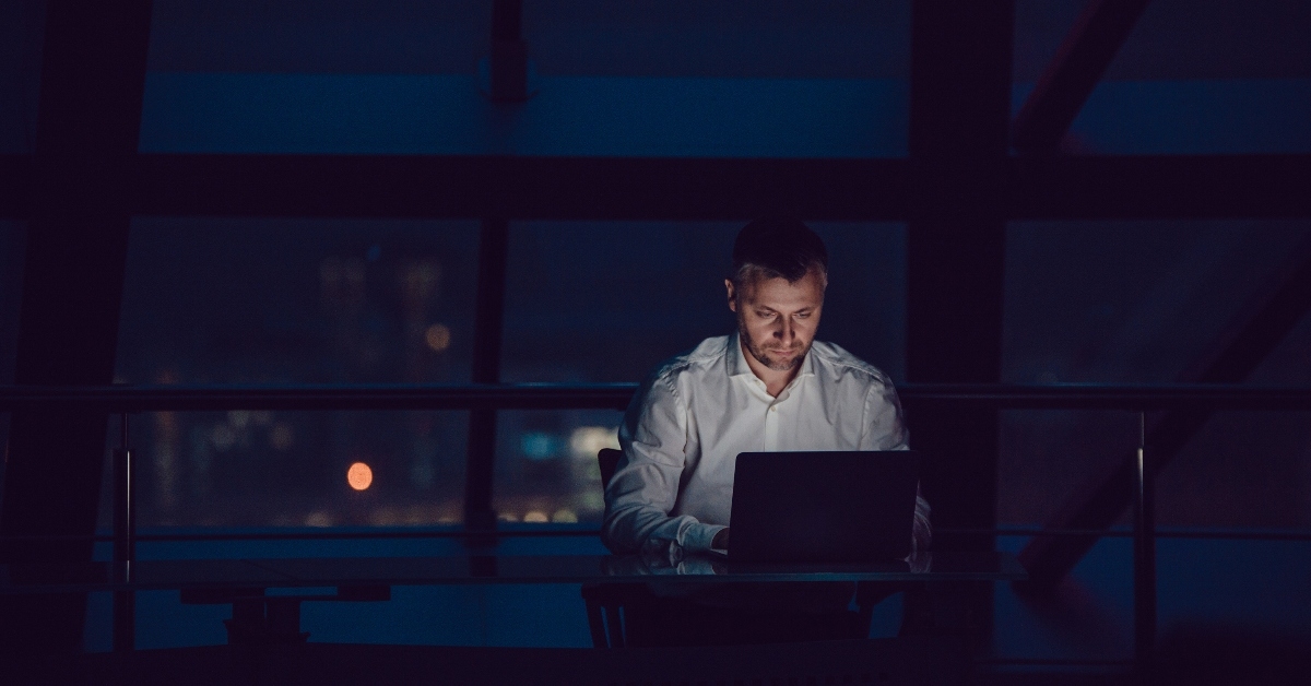 businessman in office at night working on laptop