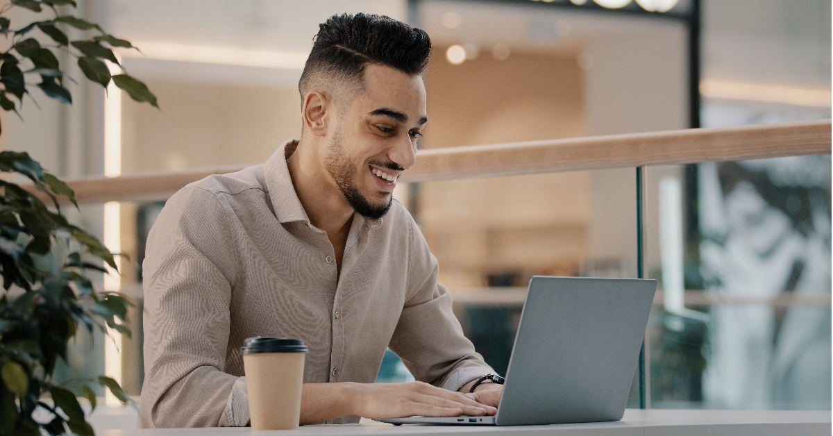 happy man doing freelance work at café using laptop