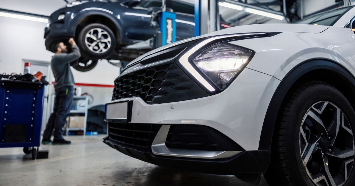 car standing at auto workshop with man repairing car in background