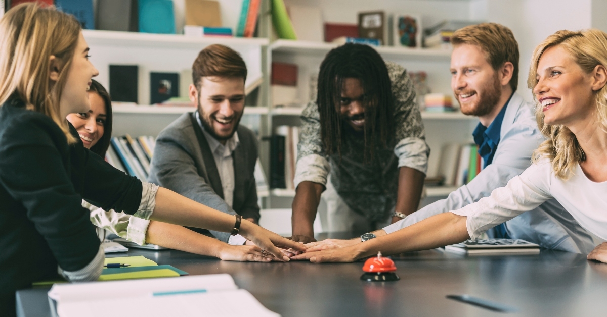 multi-ethnic employees joining hands 