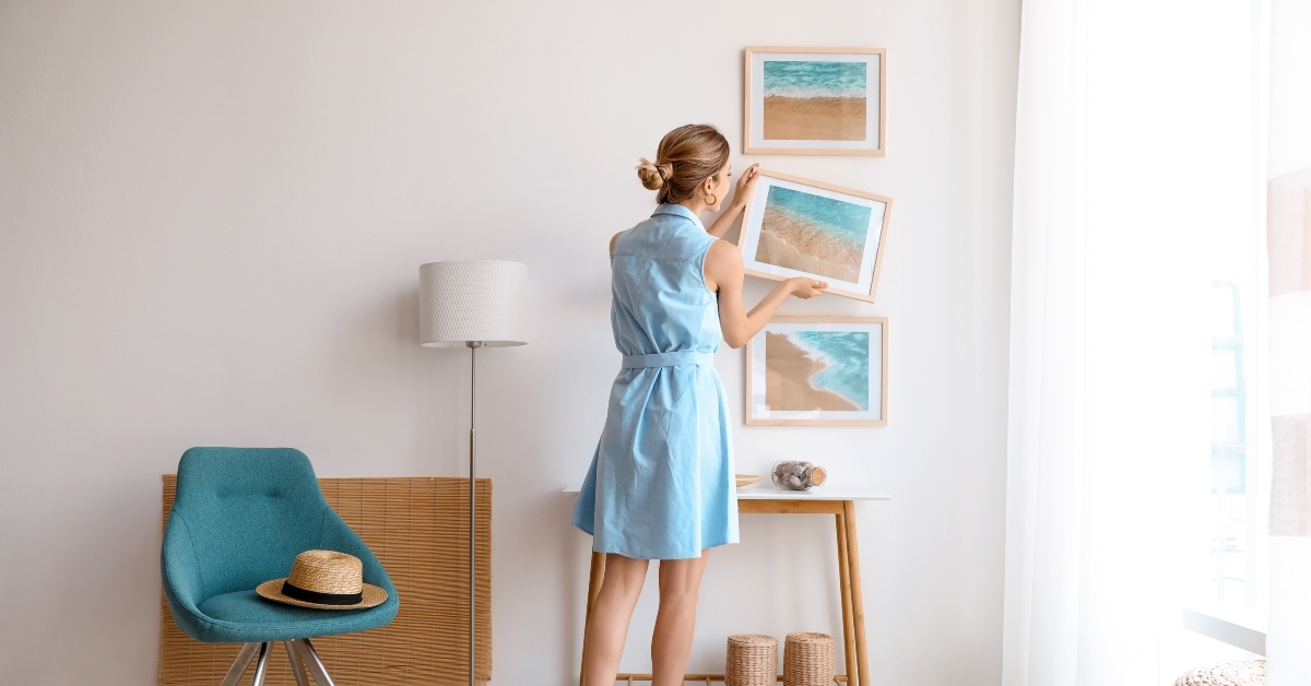 female interior designer decorating white wall with pictures