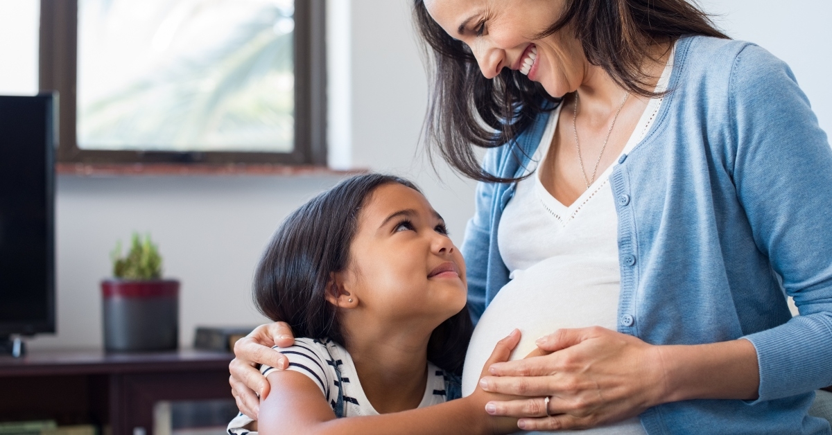 daughter touching the belly of her pregnant mother
