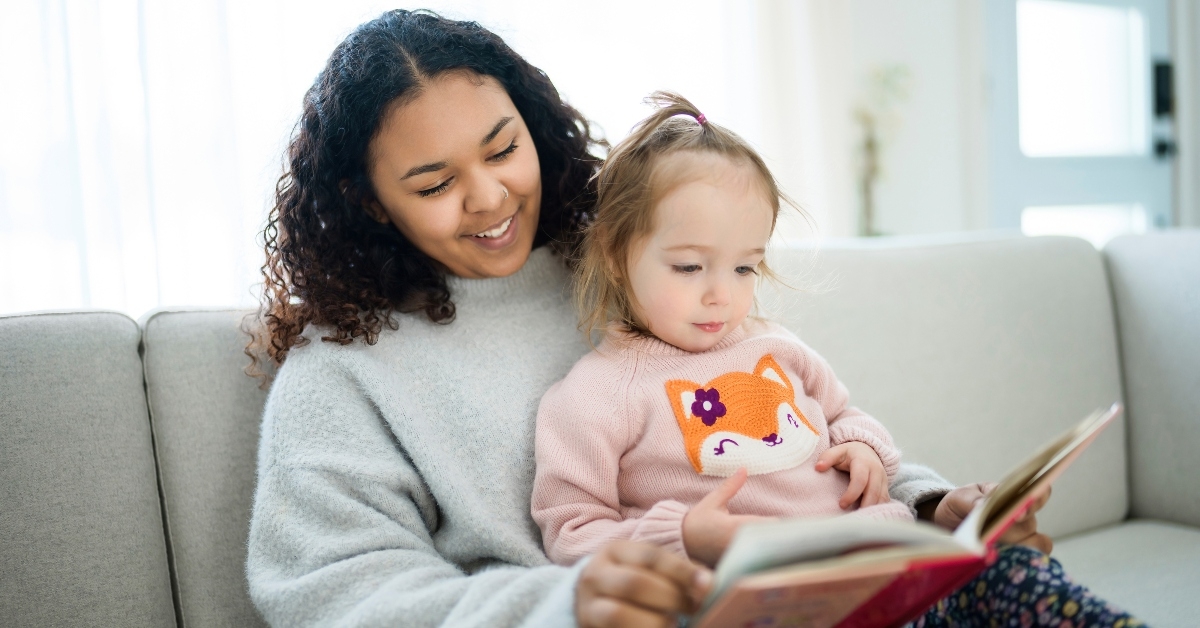 female babysitter reading book with little girl