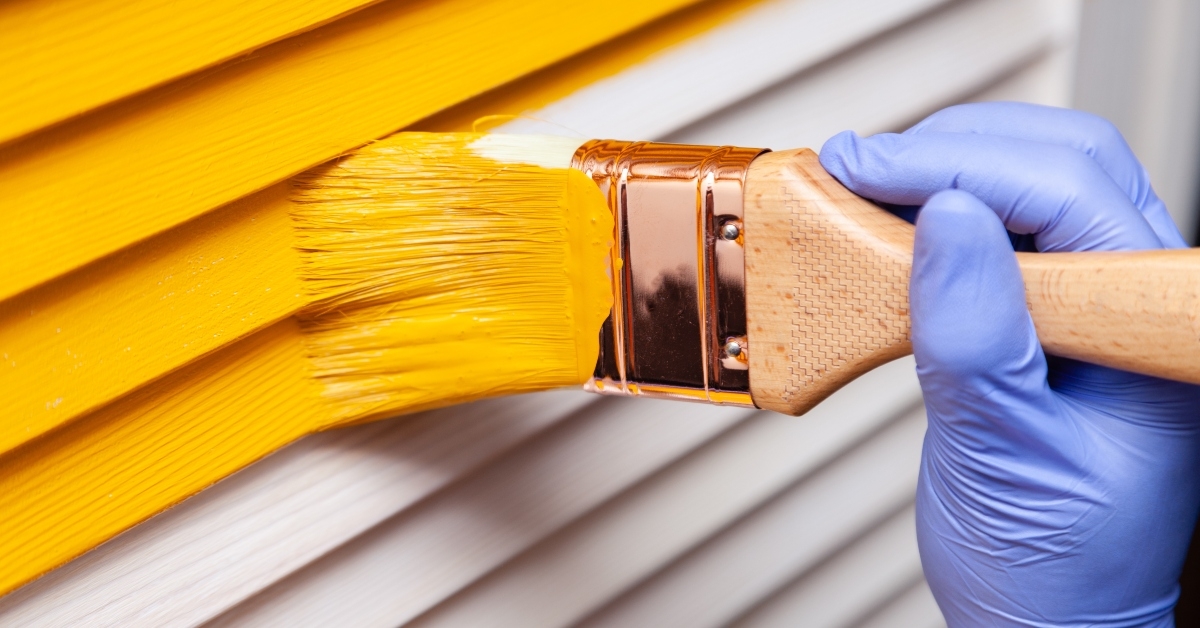 female hand in purple rubber glove with paintbrush