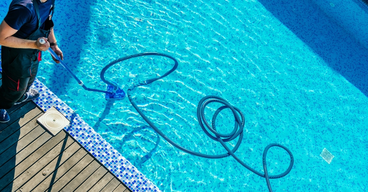 man cleaning the swimming pool with vacuum equipment